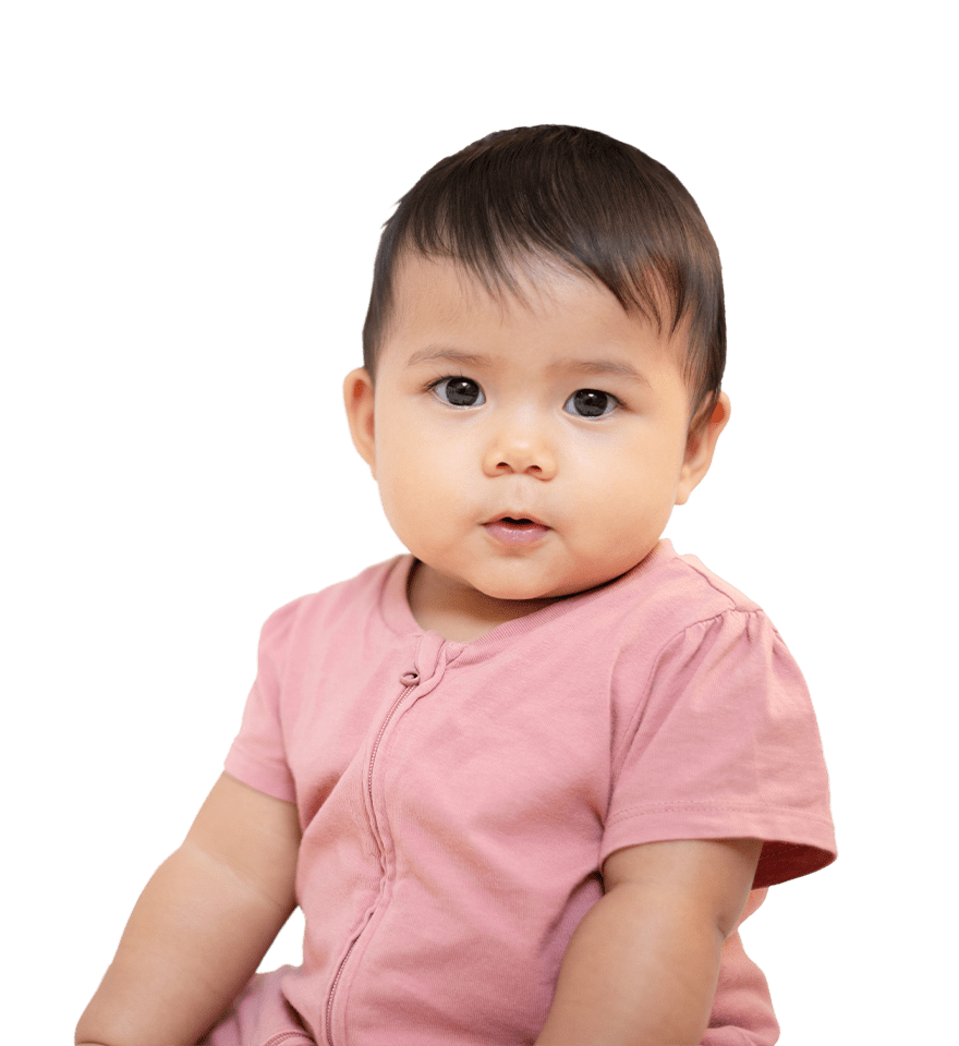 A toddler with dark hair and wide eyes wearing a pink shirt