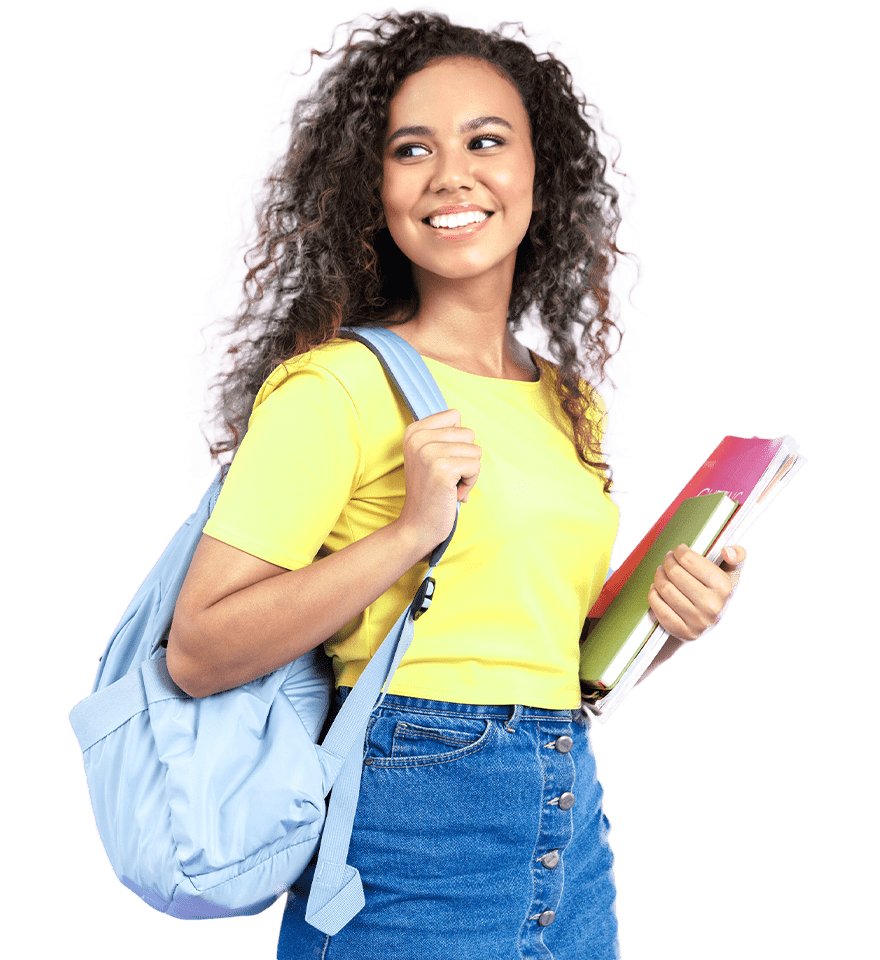 A young woman with curly hair smiles while holding textbooks and wearing a yellow t-shirt and denim jeans, carrying a blue backpack over one shoulder as she heads to her post-secondary education classes.