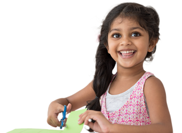 Young girl smiling while cutting a piece of paper