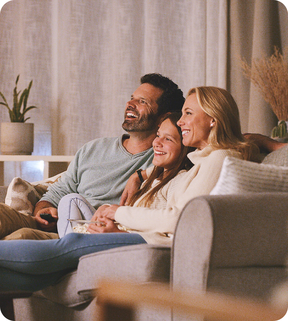 A family enjoying time together on a couch, focused on a television screen in a warm and inviting living room.
