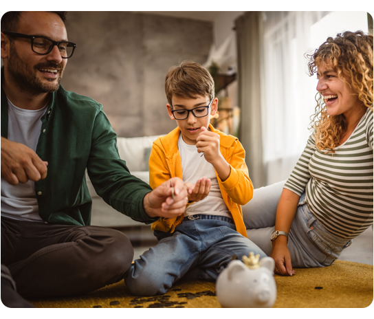 A smiling family of four counts coins and deposits them into a piggy bank