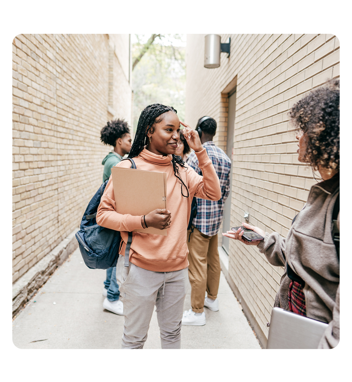 Two women engaged in conversation in a narrow alleyway, surrounded by brick walls and urban scenery.