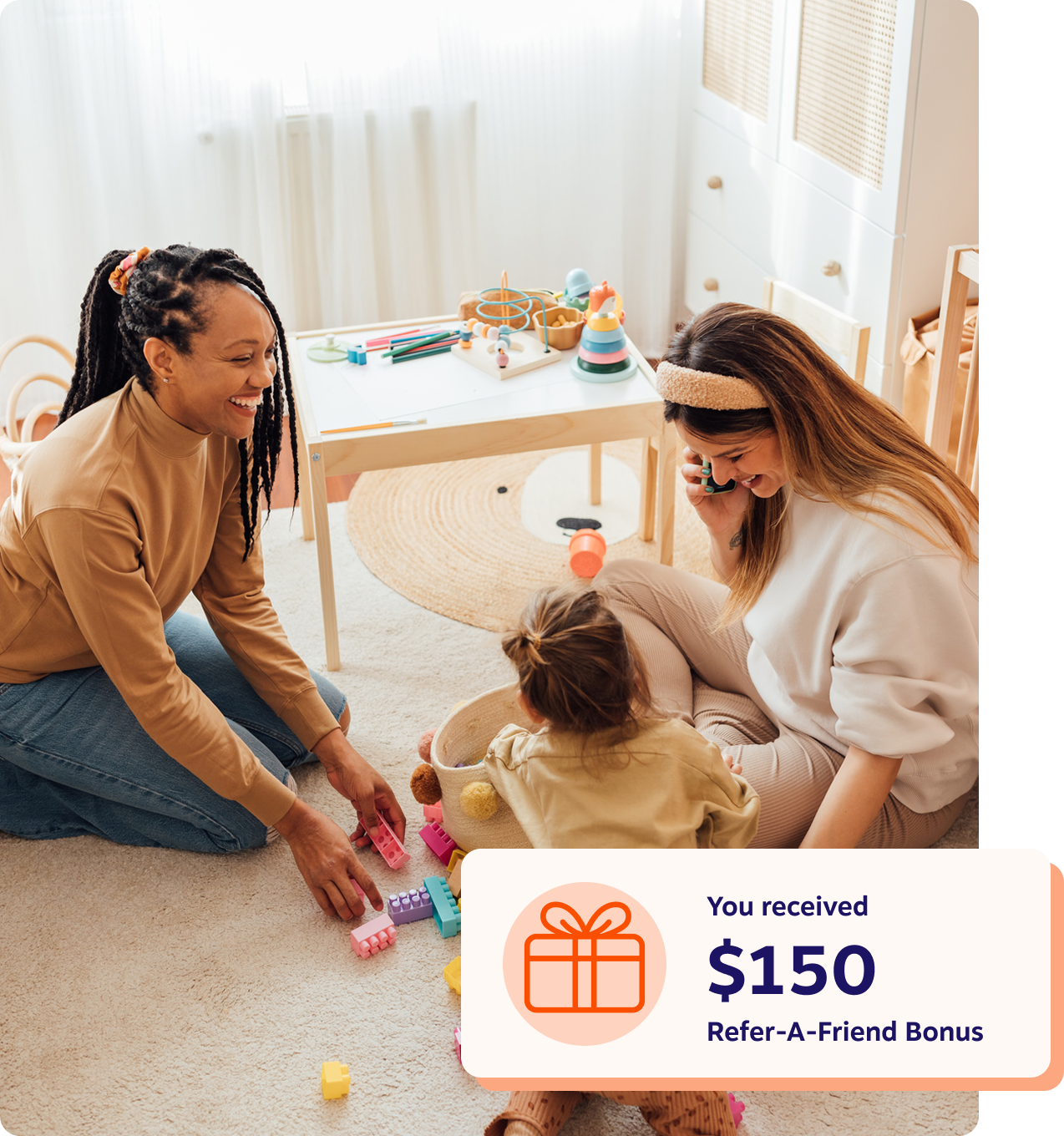 Two women playing with a toddler on the floor of a bright playroom, with a notification showing a $150 Refer-A-Friend Bonus.