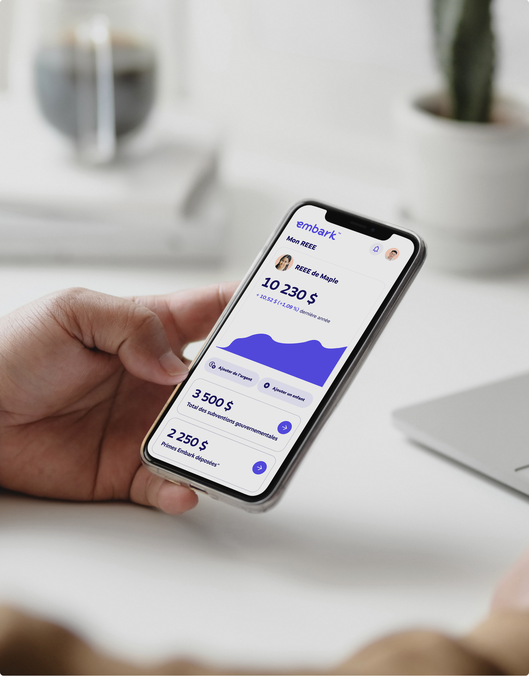 Gros plan d’une main tenant un téléphone intelligent affichant l’application Embark, montrant un REEE de 10 230 $ avec une répartition visuelle des cotisations, subventions et revenus.