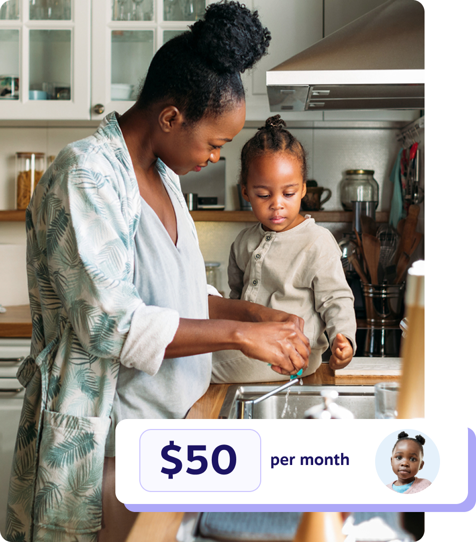 A mother washing dishes with her toddler sitting on the counter beside her