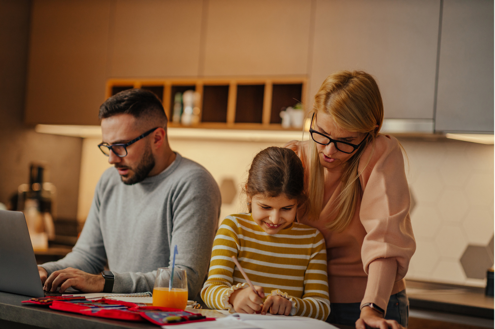 mother helping daughter with homework while dad is focused on laptop