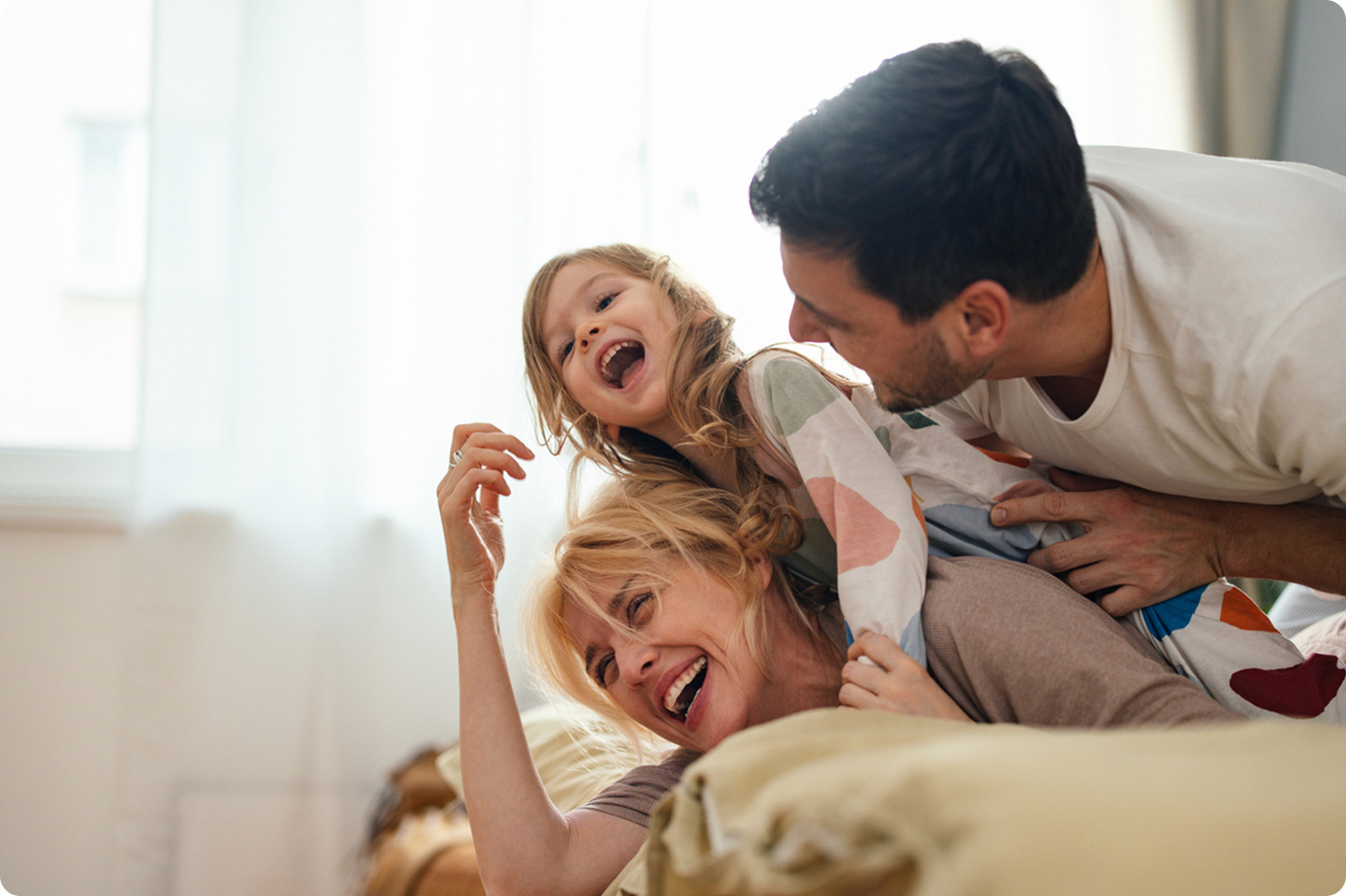 Mother and Father playing with child on mothers back laughing