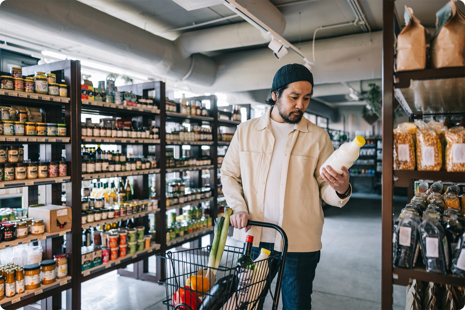 Man in grocery store looking at price-tag of product with concerned expression