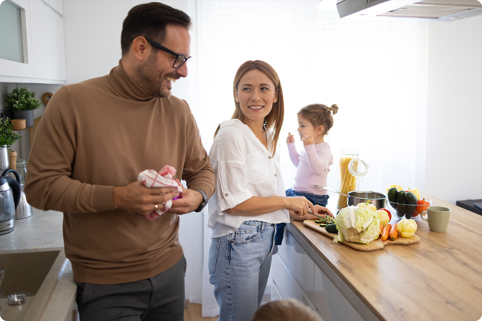 Parents are making dinner while kids sit and play in the kitchen