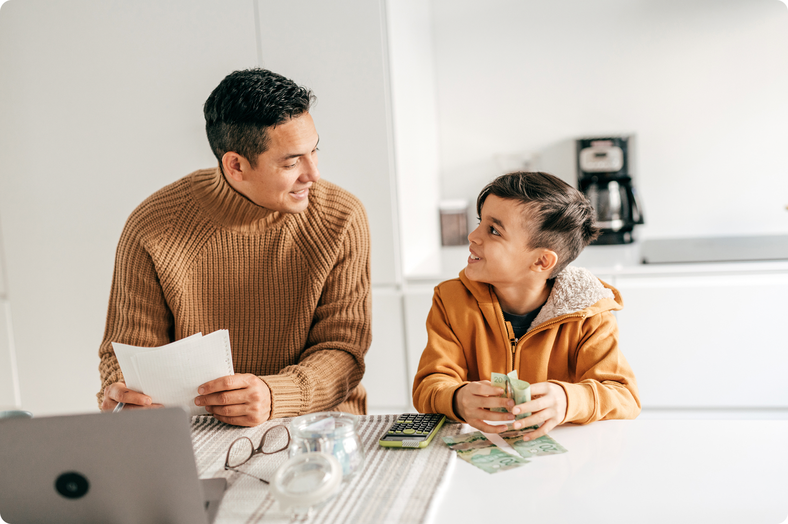 Father sitting with son, teaching him how to budget