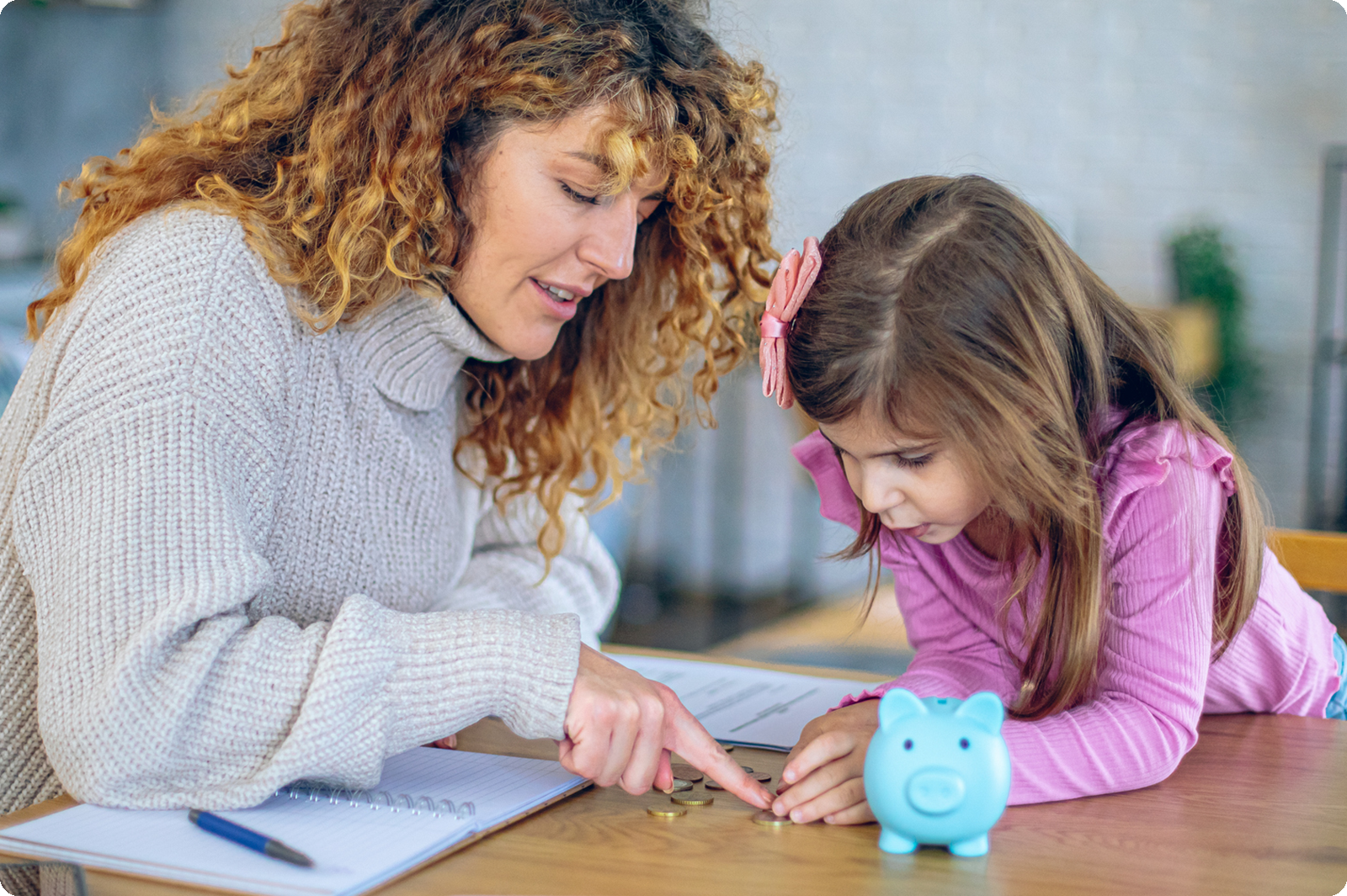 Mother teaching daughter how to count the money in her piggy bank