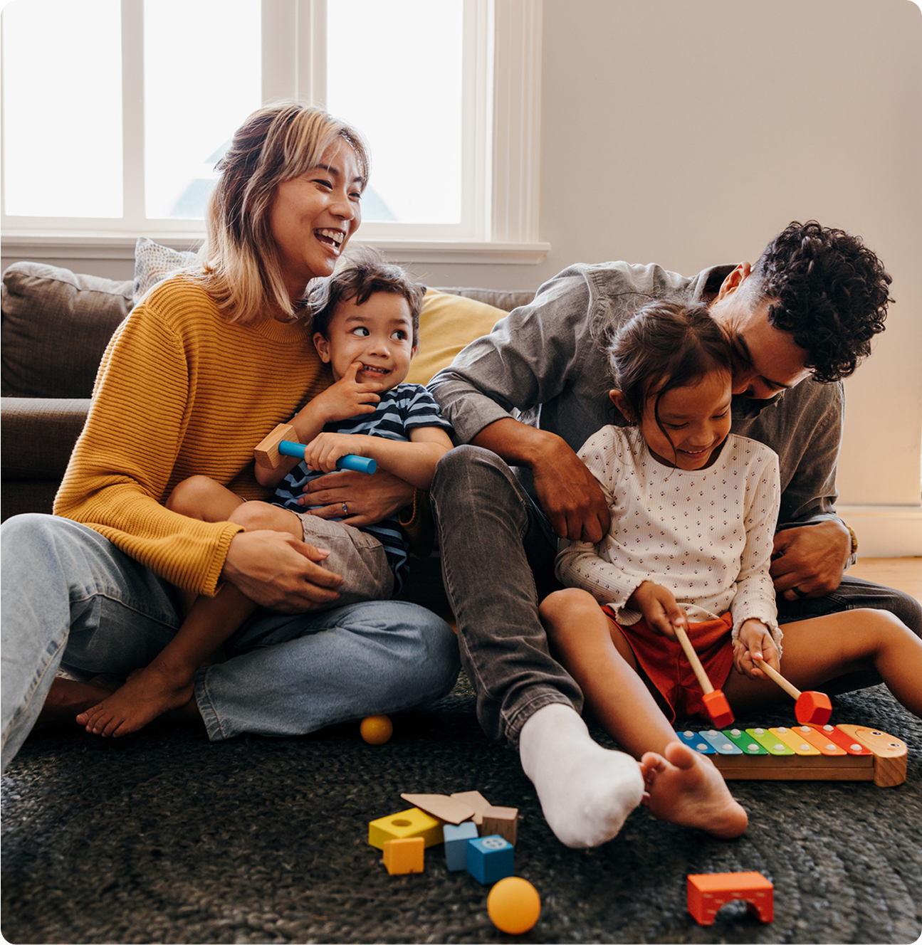 A family joyfully playing with colorful toys on the floor, surrounded by laughter and engagement.