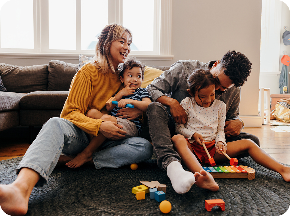 A family joyfully playing with colorful toys on the floor, surrounded by laughter and engagement.