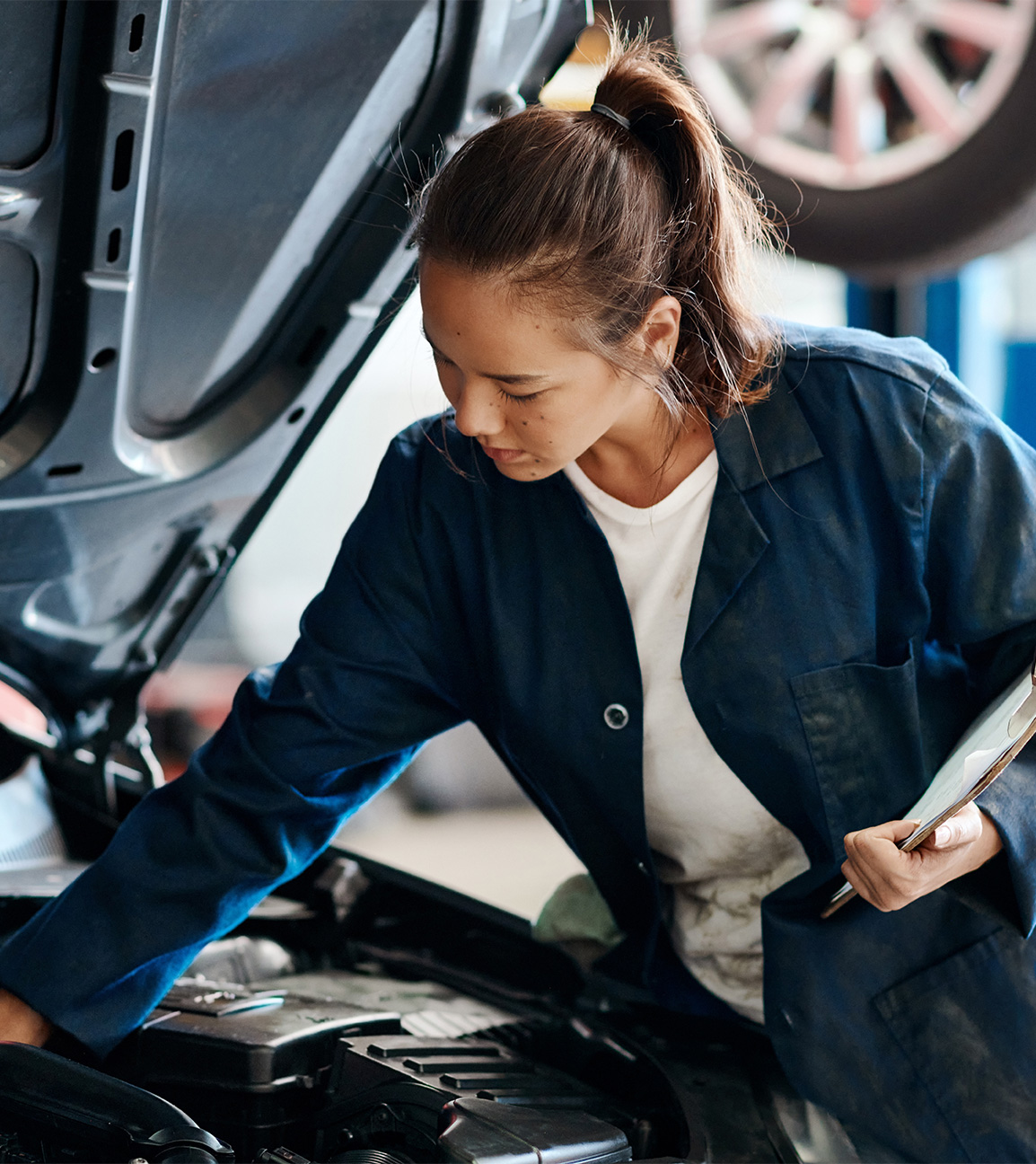 Woman mechanic looking at a car's engine